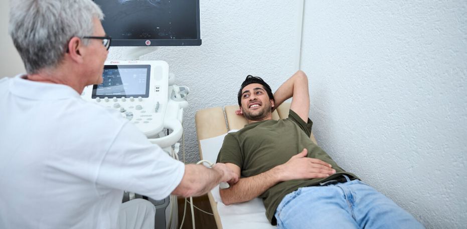 Ein Arzt untersucht per Ultraschall den Ellenbogen eines Patienten