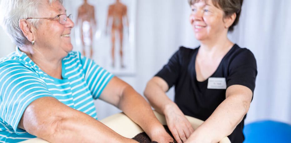 Patient taucht ihre Hände ein ins Kieselbad