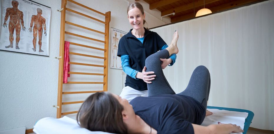 Therapeutin mobilisiert in der Physio das Bein der Patientin