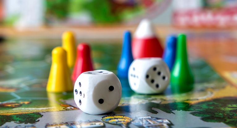 Würfel und Spielfiguren auf einem Spielbrett