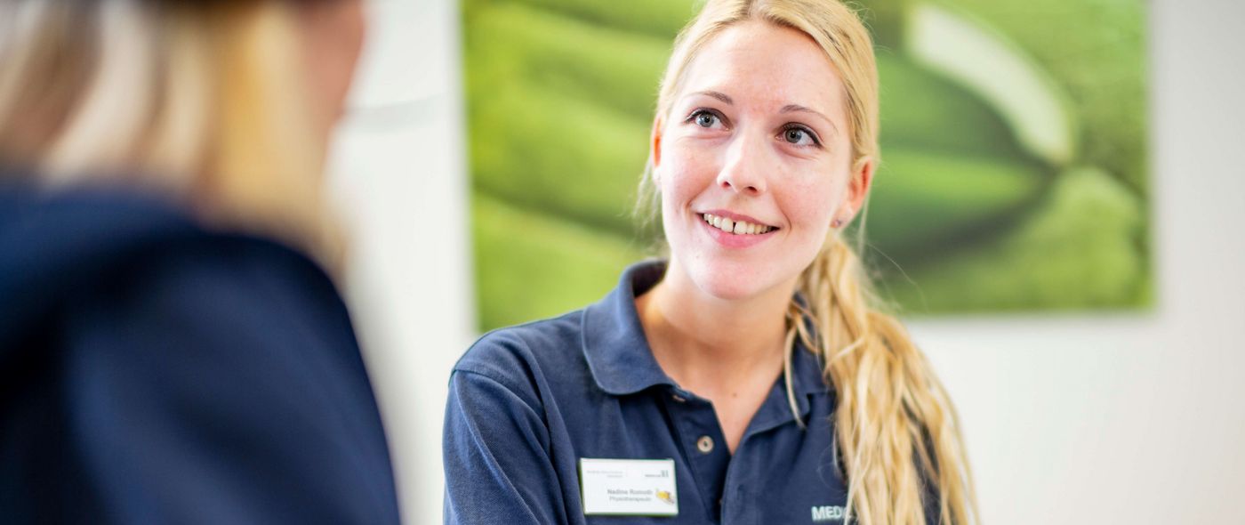 Eine Mitarbeiterin hilft einer Patientin beim Ausfüllen von Formularen