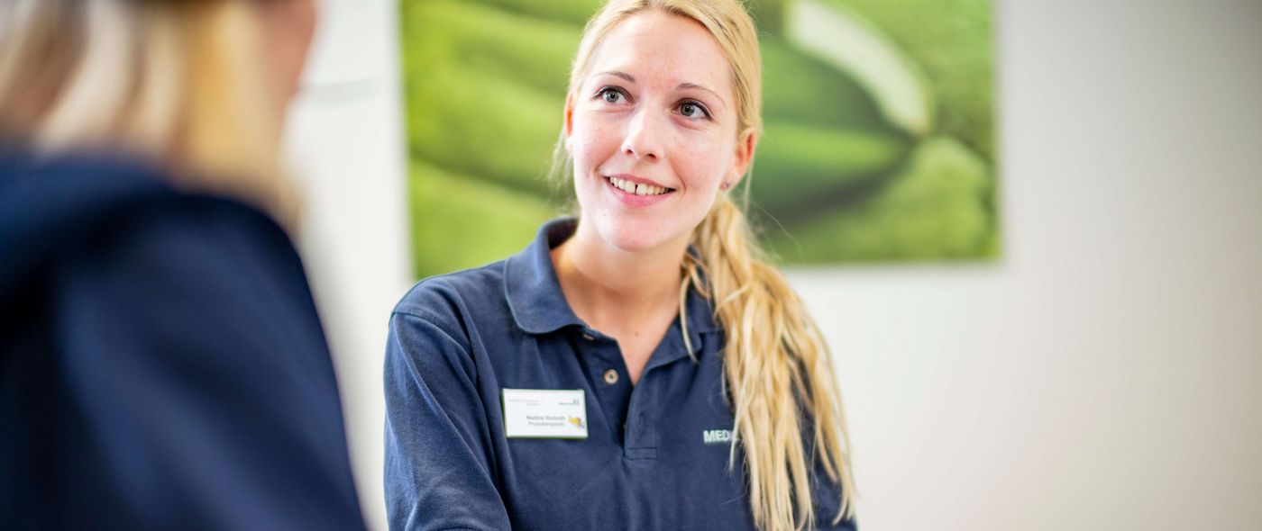 Eine Mitarbeiterin hilft einer Patientin beim Ausfüllen von Formularen