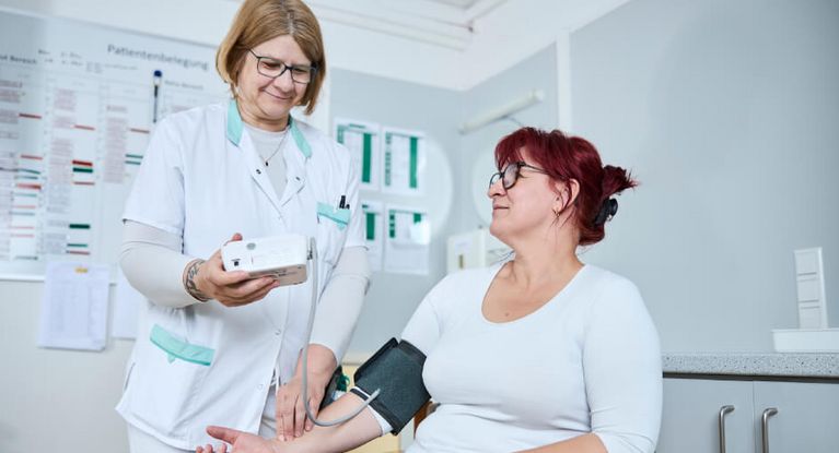 Eine Pflegekraft misst bei einer Patientin den Blutdruck