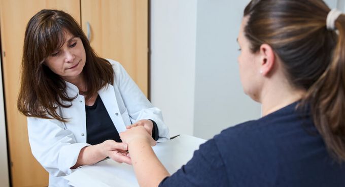 Ärztin untersucht die Hand einer Patientin