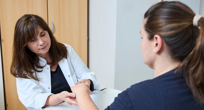 Ärztin untersucht die Hand einer Patientin